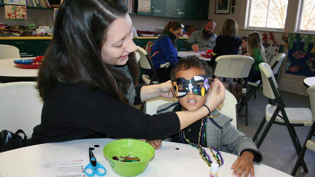 SHANNON DAVIDSON/SPECIAL TO THE SUN HERALDTegan Davis of Biloxi ties a custom-designed Mardi Gras mask on her son Deron Davis at the Children's Mardi Gras Celebration at Lynn Meadows Discovery Center on Saturday in Gulfport.