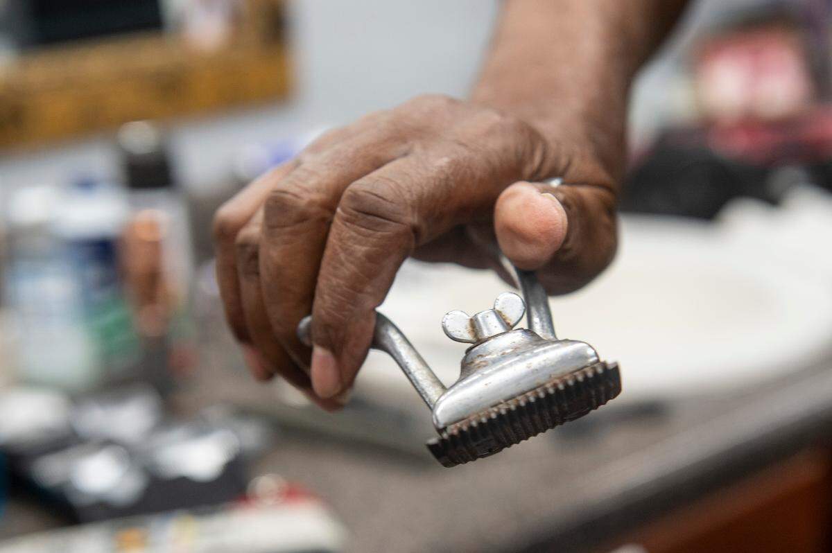 Tyrone Burton shows the clippers he used when he first started as a barber. Now, Burton who is in his 80s, has been cutting hair in Biloxi for 64 years.