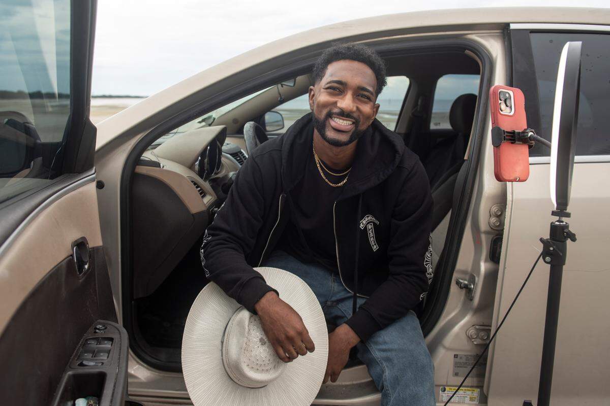 Trevor Norris, a social media star known for memes, skits and his videos of himself singing along to throwback songs, poses for a photo in his car at Jones Park in Gulfport on Wednesday, July 17, 2024.