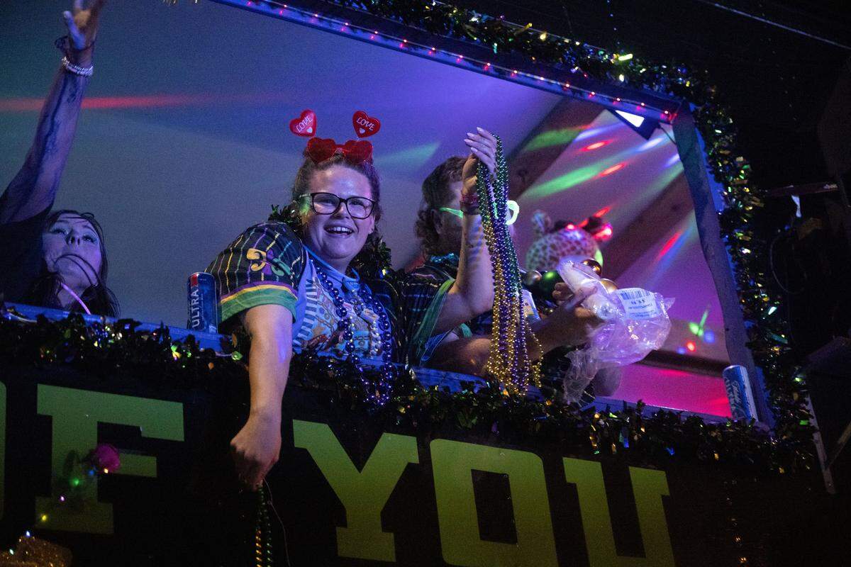 A woman passes out Mardi Gras beads from a parade float during the Krewe of Neptune parade in Biloxi on Saturday, Feb. 14, 2026.
