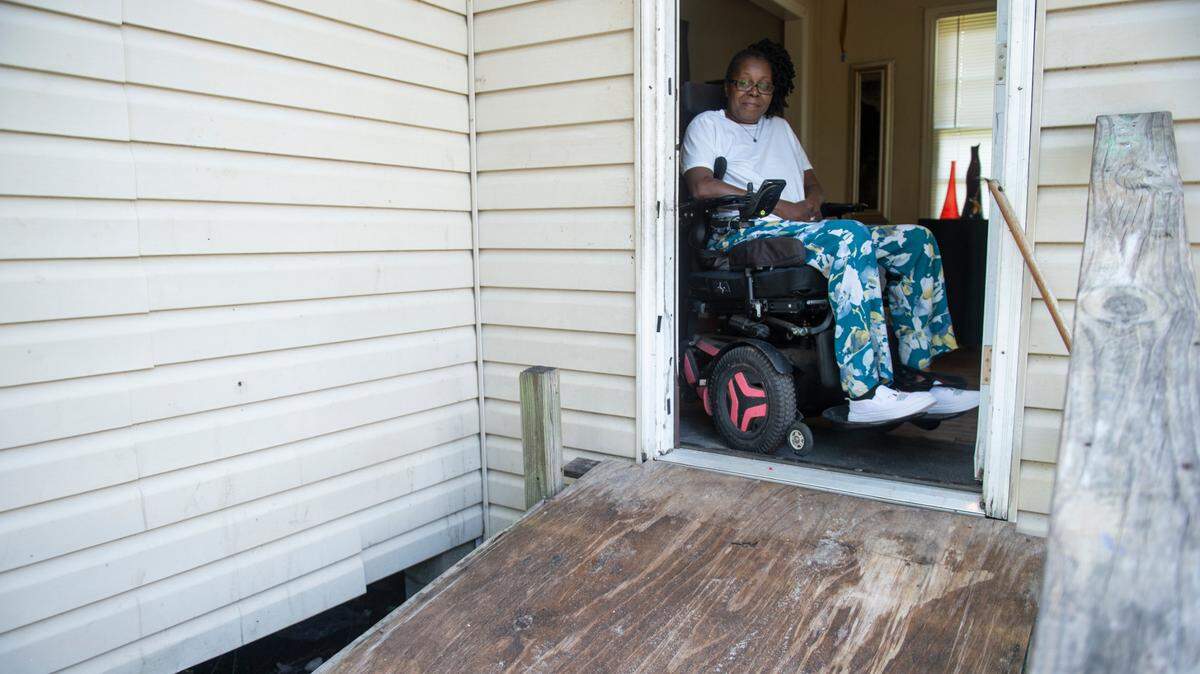 Antrease Bullock sits at the top of a makeshift wheelchair ramp at her home in Gulfport on Monday, June 10, 2024. The ramp, built by a neighbor using scrap wood, will finally be replaced with sturdier one after a nonprofit agreed to help Bullock, who was permanently disabled in a 2019 shooting.