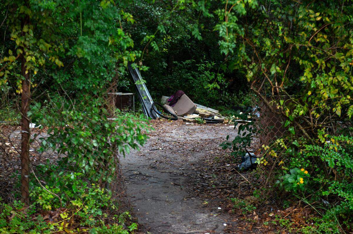 A hole in a fence leads to a trail with trash and debris on property that was once part of the defunct Broadwater Beach Resort off of Iris Street in Biloxi on Thursday, Sept. 5, 2024.
