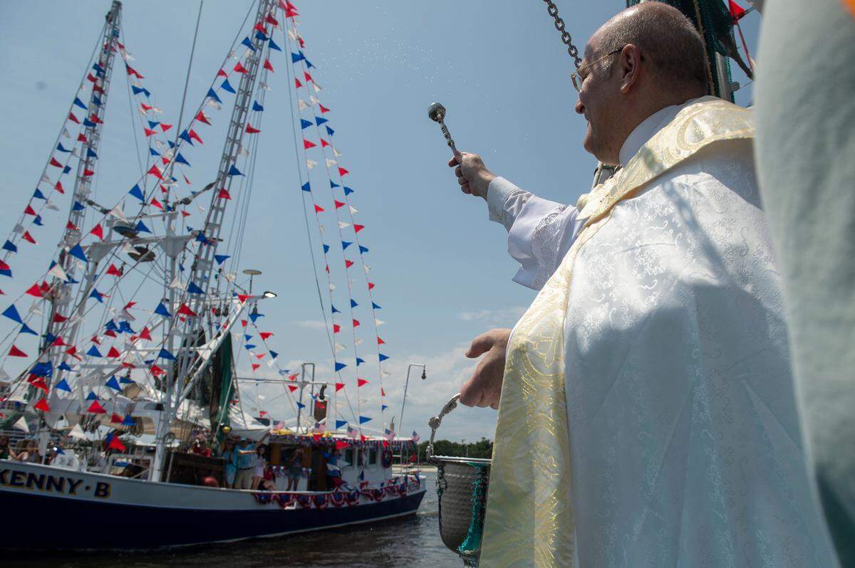 People on a boat wave to Msgr. Dominick Fullam and the Shrimp King and Queen as they receive a blessing during the Blessing of the Fleet in Biloxi on Sunday, May 28, 2023.