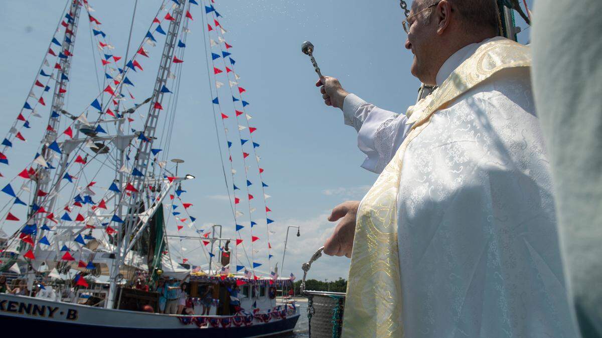 People on a boat wave to Msgr. Dominick Fullam and the Shrimp King and Queen as they receive a blessing during the Blessing of the Fleet in Biloxi on Sunday, May 28, 2023.
