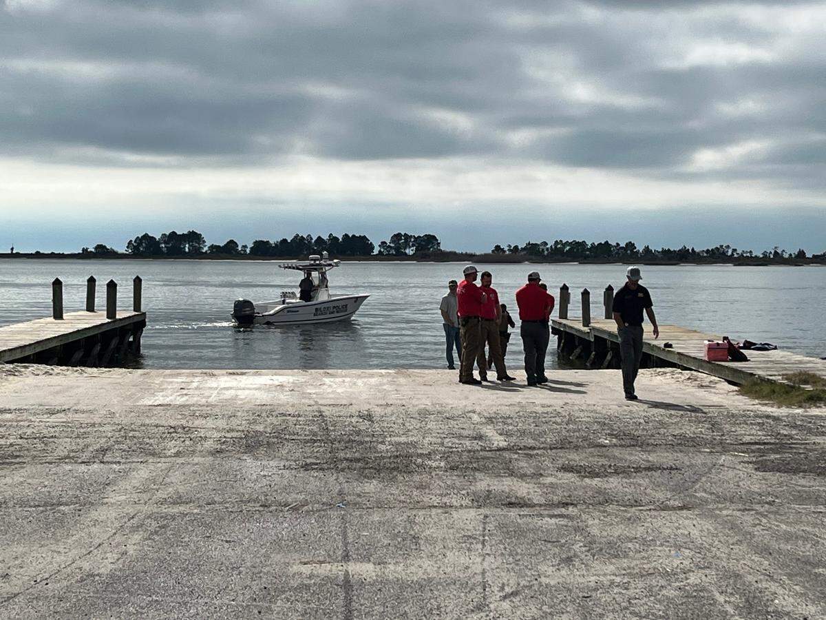 Authorities gathered at the Kuhn Street pier Tuesday morning after a paddleboarder discovered a body in the water between Biloxi and Deer Island.