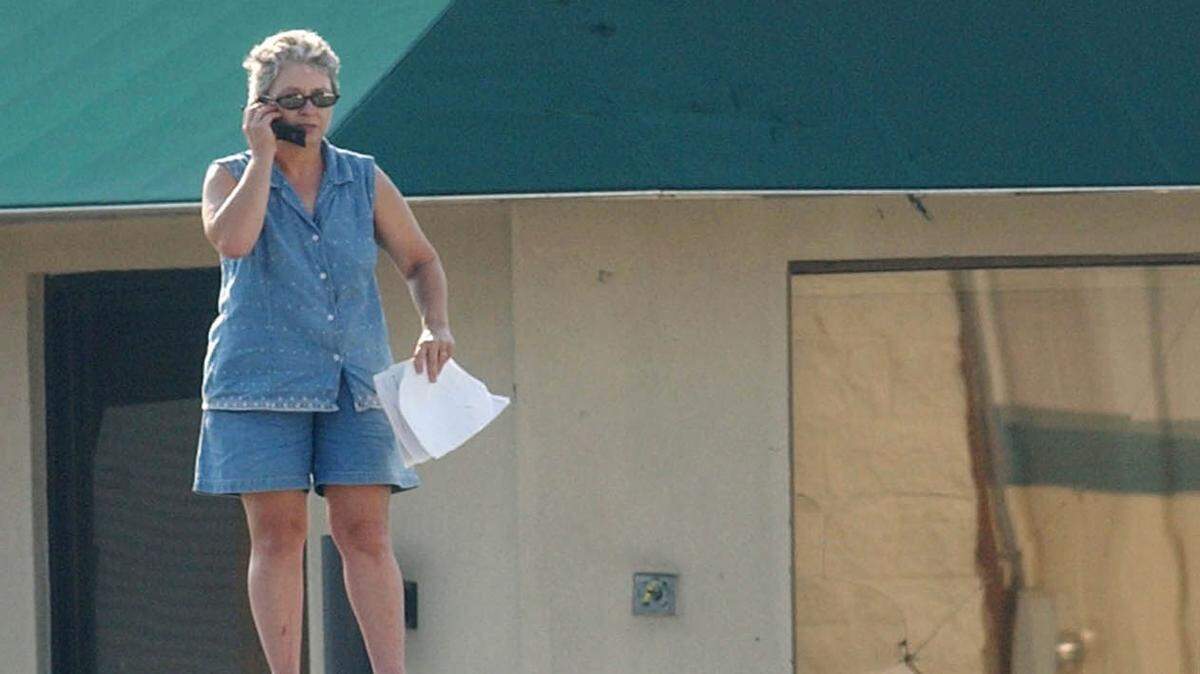 JOHN FITZHUGH/SUN HERALD/FILE 
 Nancy Madden of Gulfport stands on top of her car Sept. 2, 2005, to get a better cell signal as she and her mother, Nora Clay, try to reach family members and insurance companies following Hurricane Katrina.