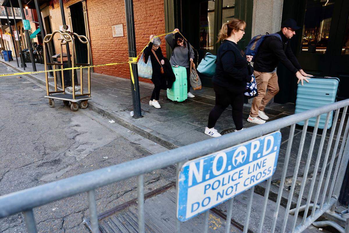 A Royal Sonesta concierge helps tourists leave past police crime tape in the French Quarter.