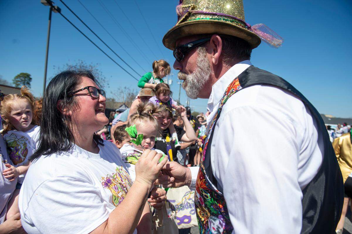 A member of the Ole Biloxi Marching Club hands out a flower during the Jackson County Carnival Association Mardi Gras parade in Pascagoula on Saturday, March 1, 2025.