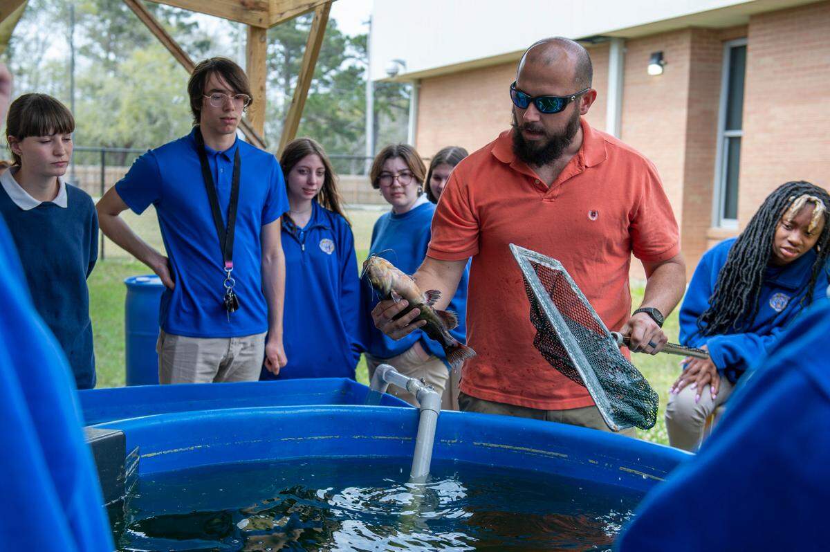 Science teacher Brent Garriga shows off a catfish to his students at Bay High School in Bay St. Louis on Tuesday, March 22, 2022. The high school has had to get creative with its science classes, often having class outside when the weather permits due to only having one science lab.
