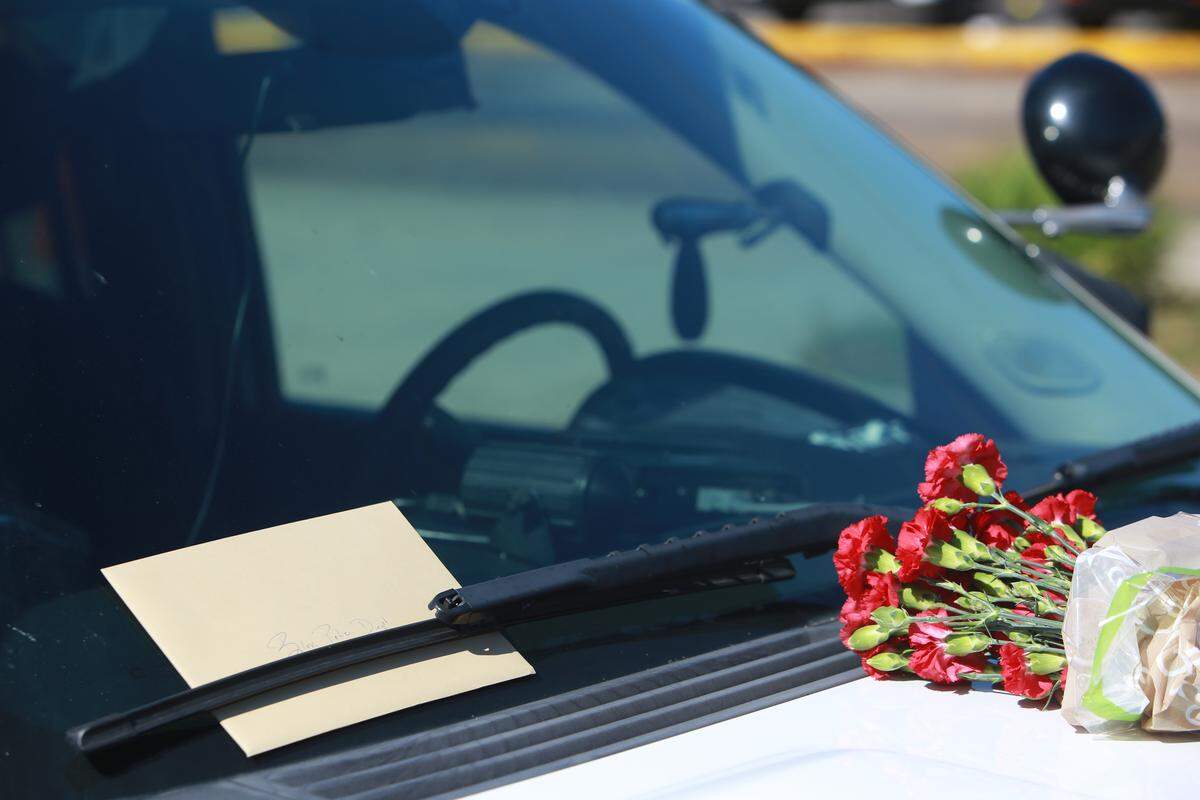 Biloxi Police Chief John Miller places flowers and a card on the police SUV of officer Robert McKeithen, killed in the line of duty on Sunday, May 5, 2019, outside the Biloxi Police Department. A manhunt is underway to find the suspect, who shot McKeithen multiple times, police say.