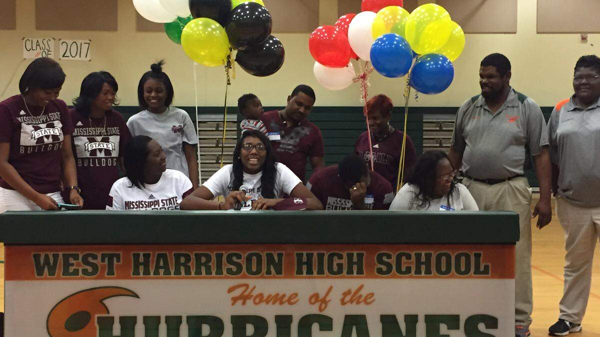 PATRICK OCHS/SUN HERALD 
 Flanked by friends, family and coaches, Weat Harrison's Ameshya Williams, middle, signed a basketball scholarship with Mississippi State on Wednesday. Also pictured is Dwayna Kennedy, Judy Ashley, Florence Williams, Kaniya Crosby, Lilplies Hall, Charlie Hall III, Jonathan Ellis, Earnestine Williams, Geneva Reed, Otis Gates and Darlene Burney.