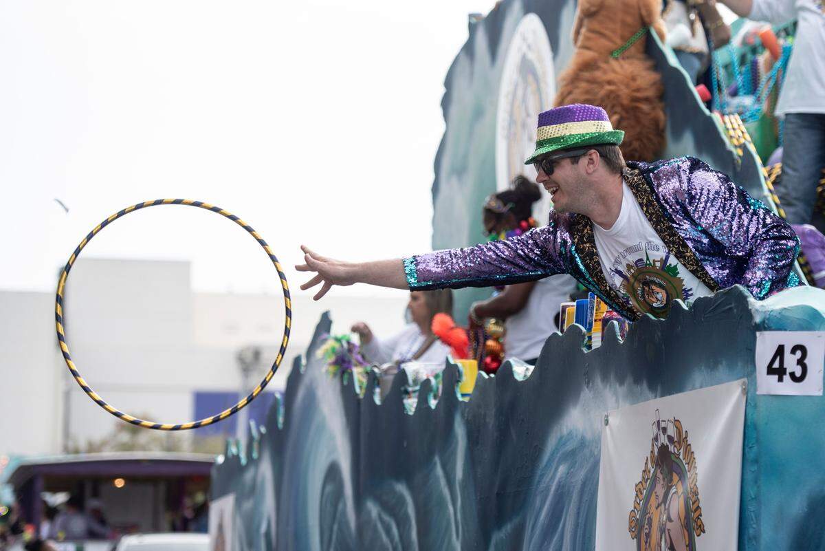 A float rider throws a hula hoop to the crowd during the Gulf Coast Carnival Association Mardi Gras parade in Biloxi on Tuesday, March 4, 2025.