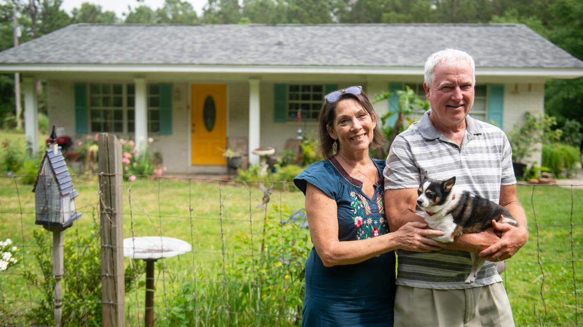 Tami Curtis Guy, her husband Perry Guy, and their dog Tippi pose for a photo outside their home in Bay St. Louis on Monday, April 29, 2024. The Guys were granted a FEMA grant to elevate their home to protect from flooding but they say the city of Bay St. Louis has delayed the project.
