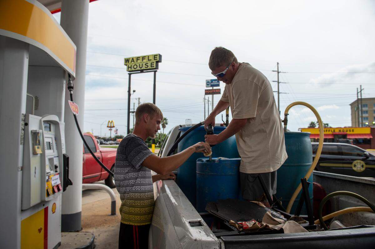 Hank Doherty, 26, and Brandon Traylor, 26, of Chalmette, Louisiana fill up gas containers to bring back to Louisiana for their families on Wednesday, Sept. 1, 2021.