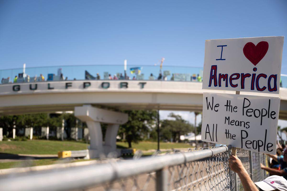 Protesters hold signs up to cars as they pass by. 