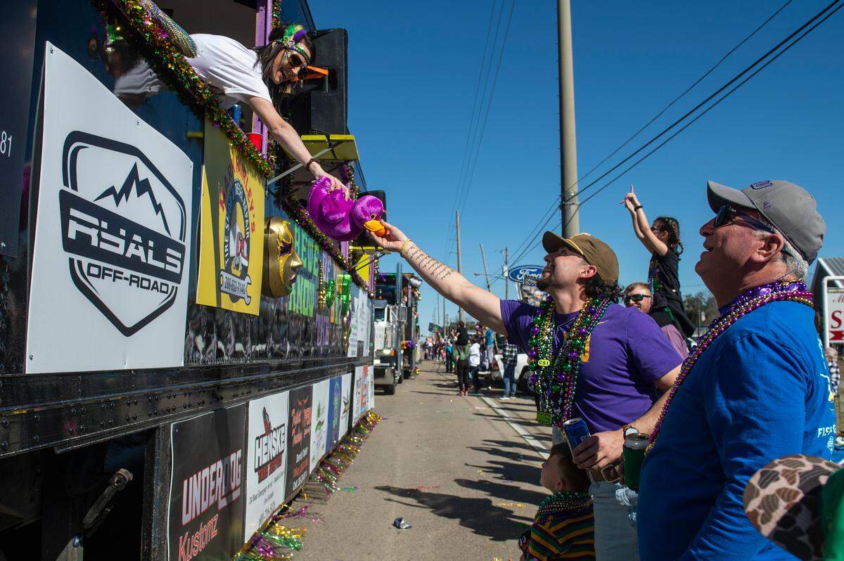 A float rider hands a stuffed duck to the crowd during the Krewe of Nereids Mardi Gras parade on Highway 90 in Bay St. Louis on Sunday, Feb. 12, 2023.