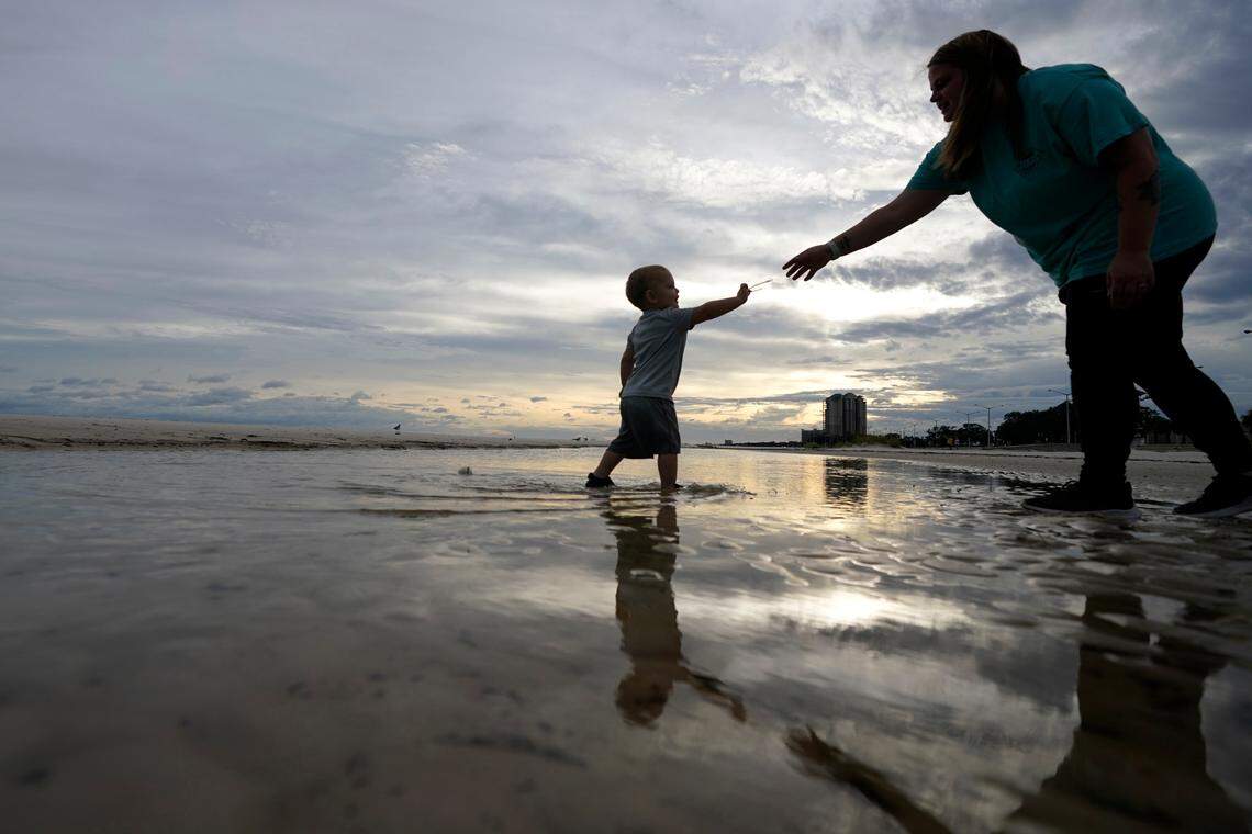 Nikita Pero of Gulfport, Miss., walks with her son Vinny Pero, 2, on the beach along the Gulf of Mexico in Biloxi, Miss., Monday, Sept. 14, 2020. (AP Photo/Gerald Herbert)