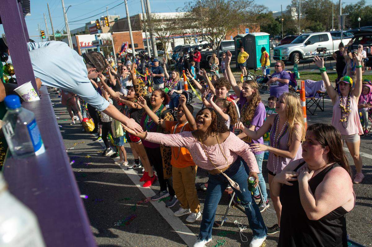 A float rider high-fives a parade-goer during the Gulf Coast Carnival Association Mardi Gras parade in Biloxi on Tuesday, Feb. 21, 2023.