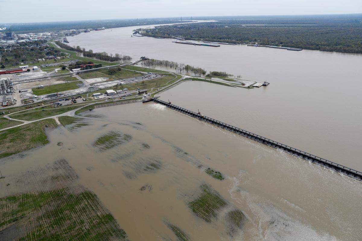 In this March 8, 2018 file photo, workers open the gates of the Bonnet Carre spillway, a river diversion structure, which diverts water from the rising Mississippi River, above right, to Lake Pontchartrain, in Norco, Louisiana.