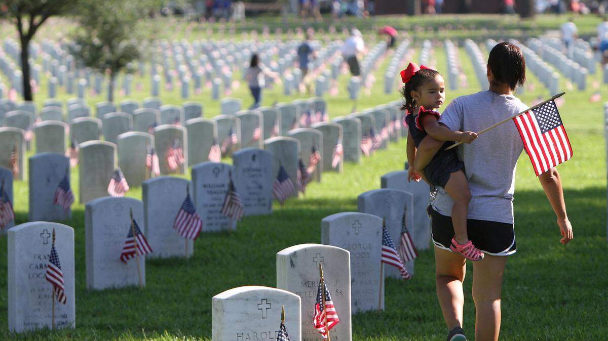 JOHN FITZHUGH/SUN HERALD/FILEAir Force veteran Demi Richard of Ocean Springs carries her daughter, Gianna, 2, through the Biloxi National Cemetery after helping place flags at the graves for Memorial Day in 2015.