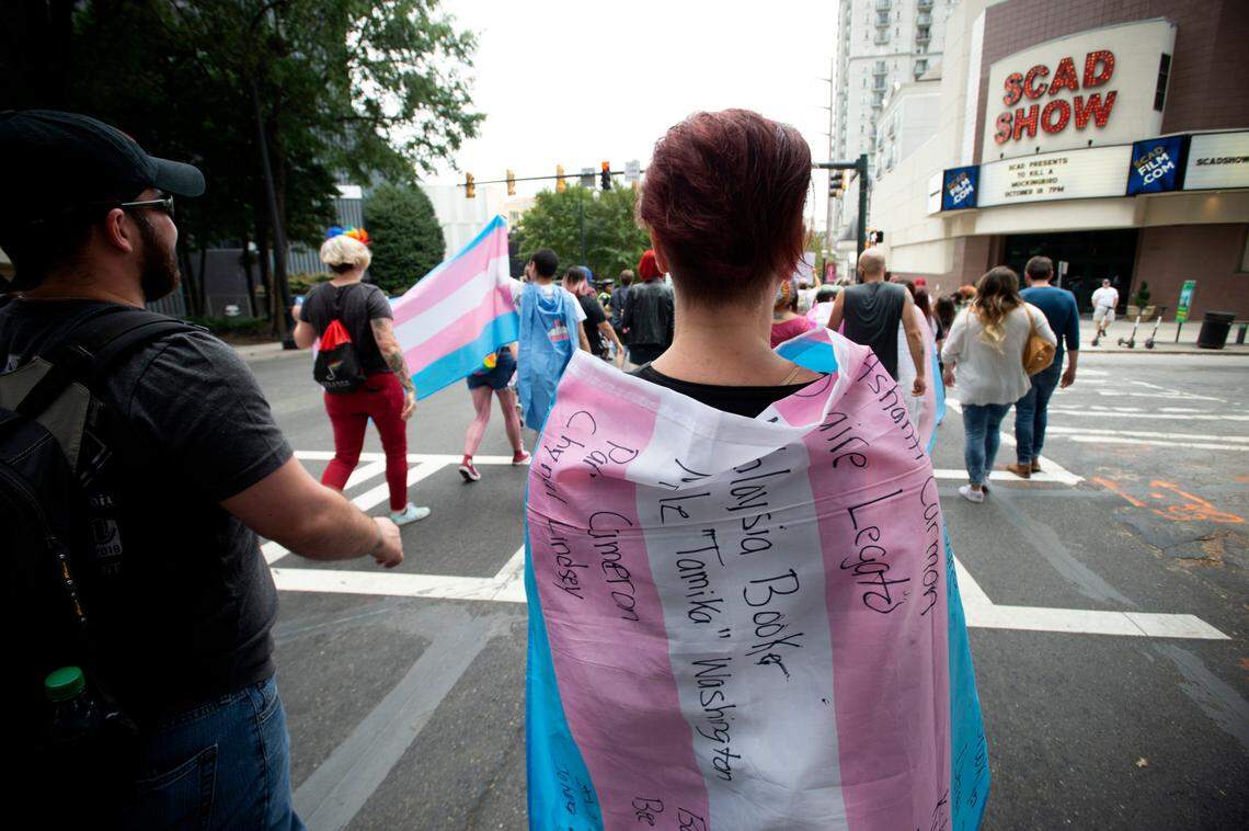 A supporter for the transgender and non-binary community, wearing a transgender flag with handwritten names of Black trans women who the person said were killed in 2019. (AP Photo/Robin Rayne)