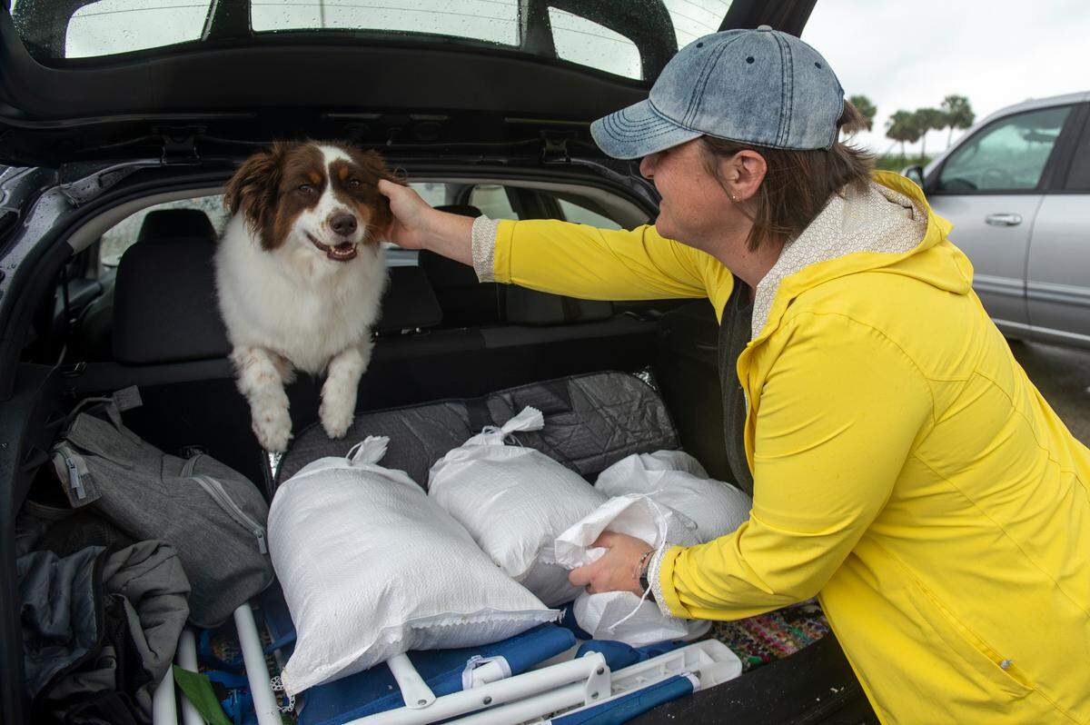 Lindsey Ranney and her dog Fig fill the trunk of Ranney’s car with sandbags in preparation for Hurricane Francine. They filled the bags from a pile of sand provided by Harrison County at the end of Courthouse Road in Gulfport on Tuesday, Sept. 10, 2024.