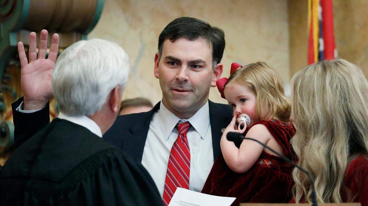 Secretary of State Michael Watson holds his youngest daughter, Cora Elizabeth, 18 months, as he is sworn into office by Mississippi Supreme Court Chief Justice Michael Randolph, left, in House chambers at the Mississippi Capitol in Jackson, Miss., Thursday, Jan. 9, 2020.