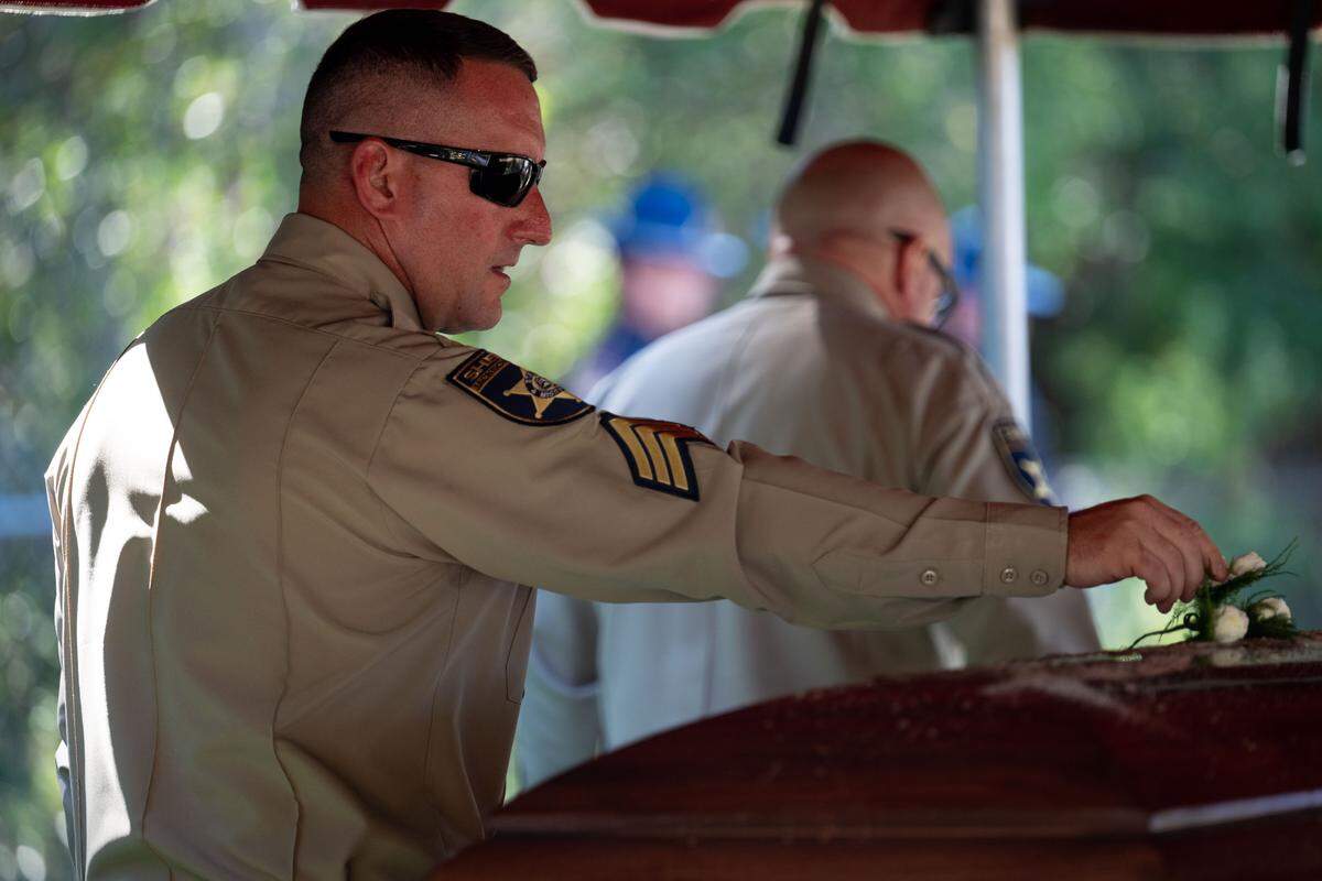 Lionel Bourgeois places a flower on Joshua Brashears’ casket Wednesday.