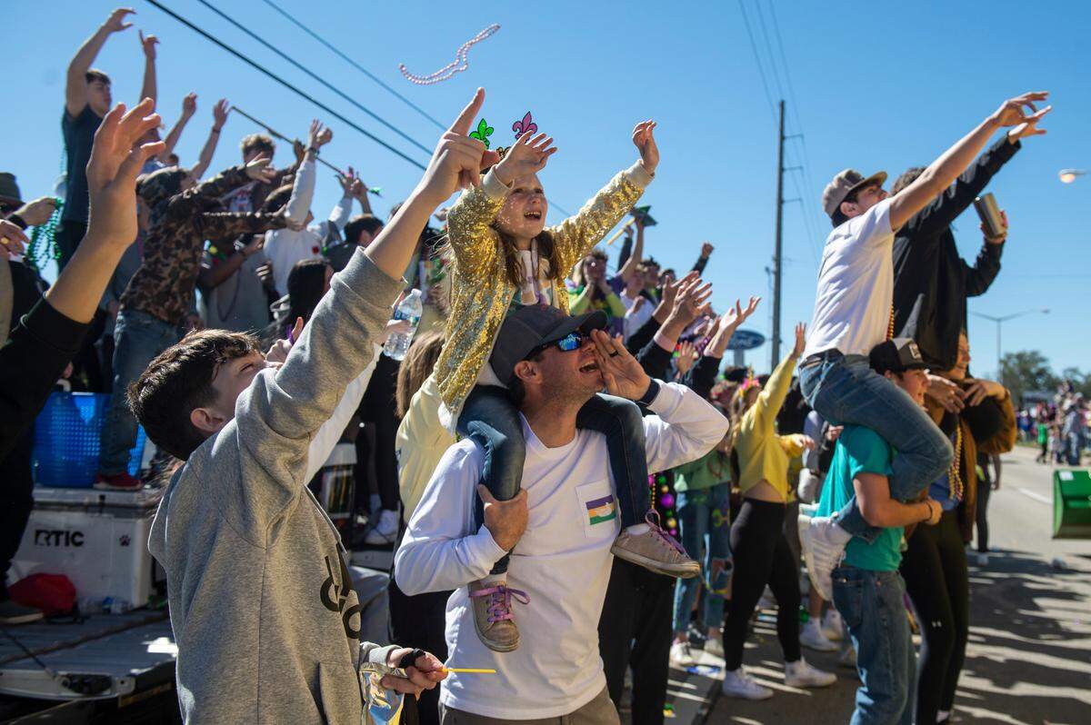 Parade watchers cheer as floats go by during the Krewe of Nereids Mardi Gras parade on Highway 90 in Bay St. Louis on Sunday, Feb. 12, 2023.