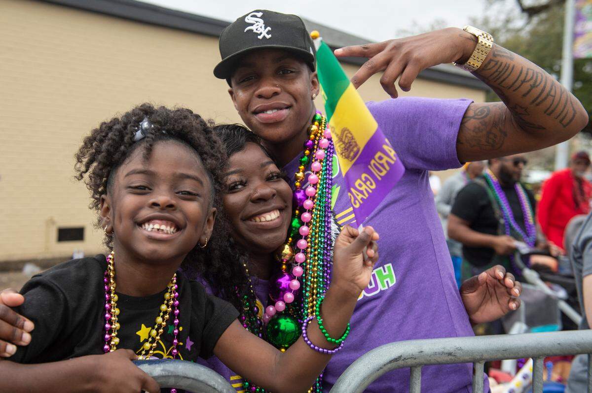 Parade watchers pose for a photo during the Gulf Coast Carnival Association Mardi Gras parade in Biloxi on Tuesday, March 4, 2025.