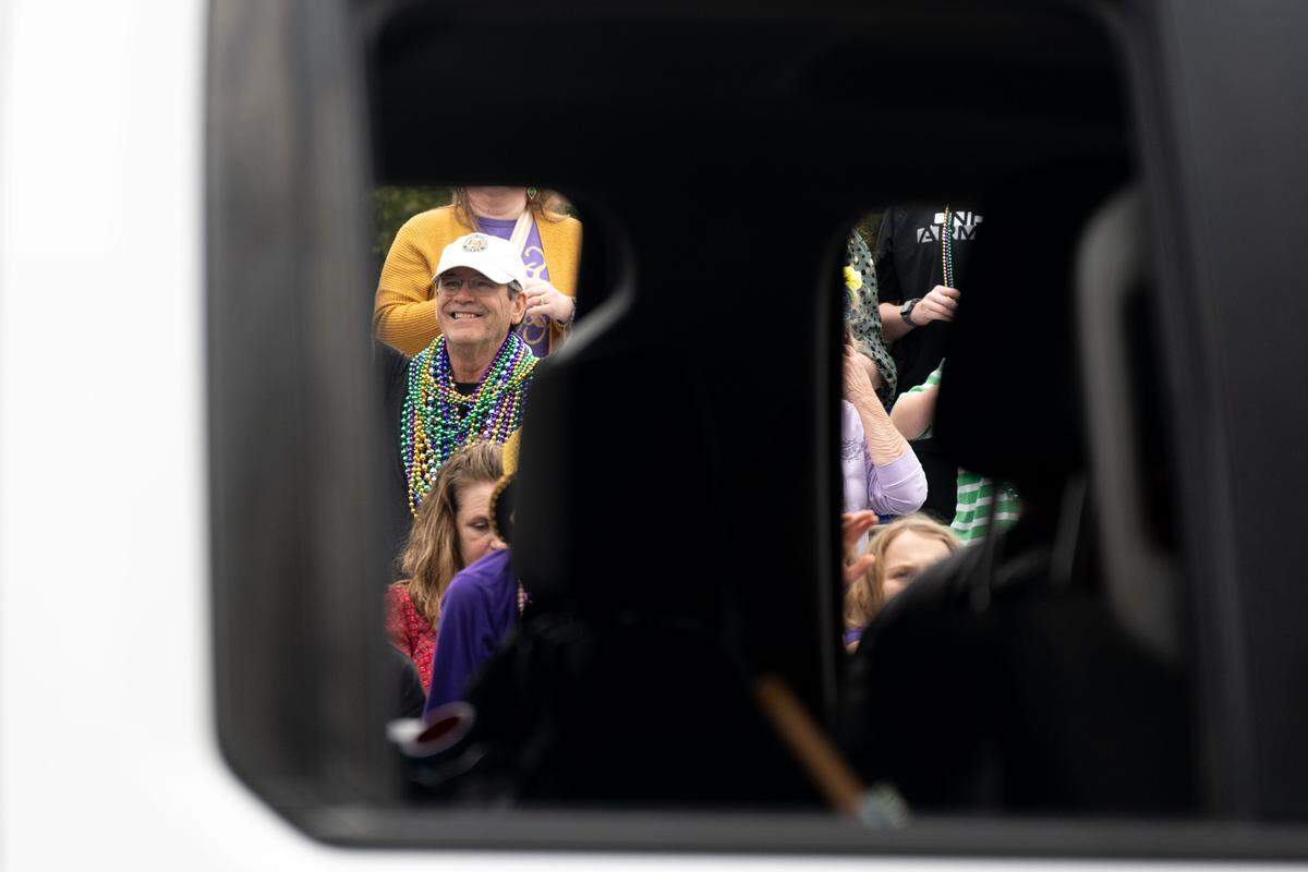 Members of the crowd smile as floats pass by.