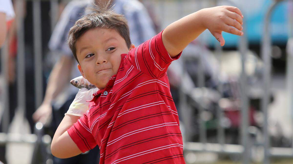AMANDA McCOY/SUN HERALDDenilson Martinez, 6, winds up for a big throw while tossing mullet at the 2015 Gautier Mullet and Music Fest on Saturday. The event ends today and it also offers live music, vendors, food, activities for children, a car show and more.