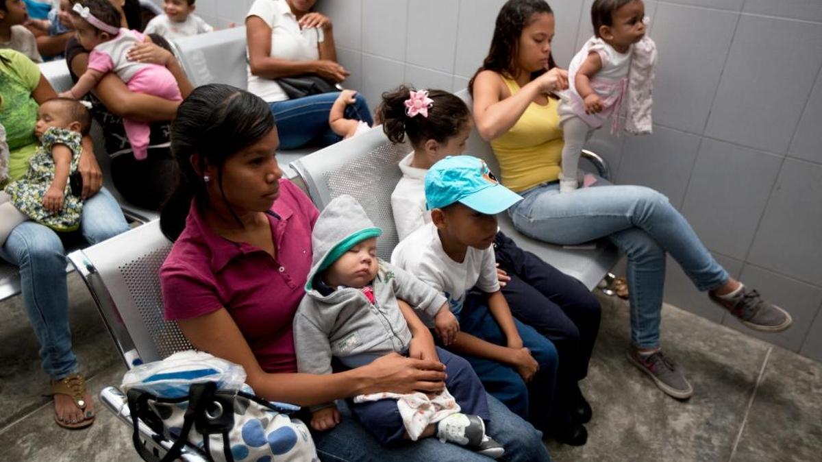 In this Feb. 11, 2016, photo, women and children wait to see a doctor at a medical center near the Petare neighborhood in Caracas, Venezuela.