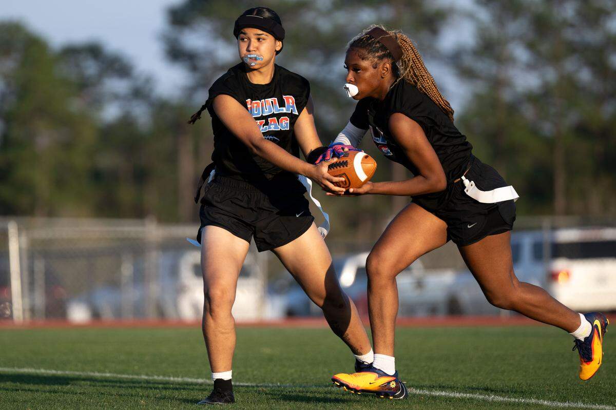 Pascagoula’s Genesis Delgado hands the ball off to Abby Mosley during a flag football game at George County High School on Thursday.