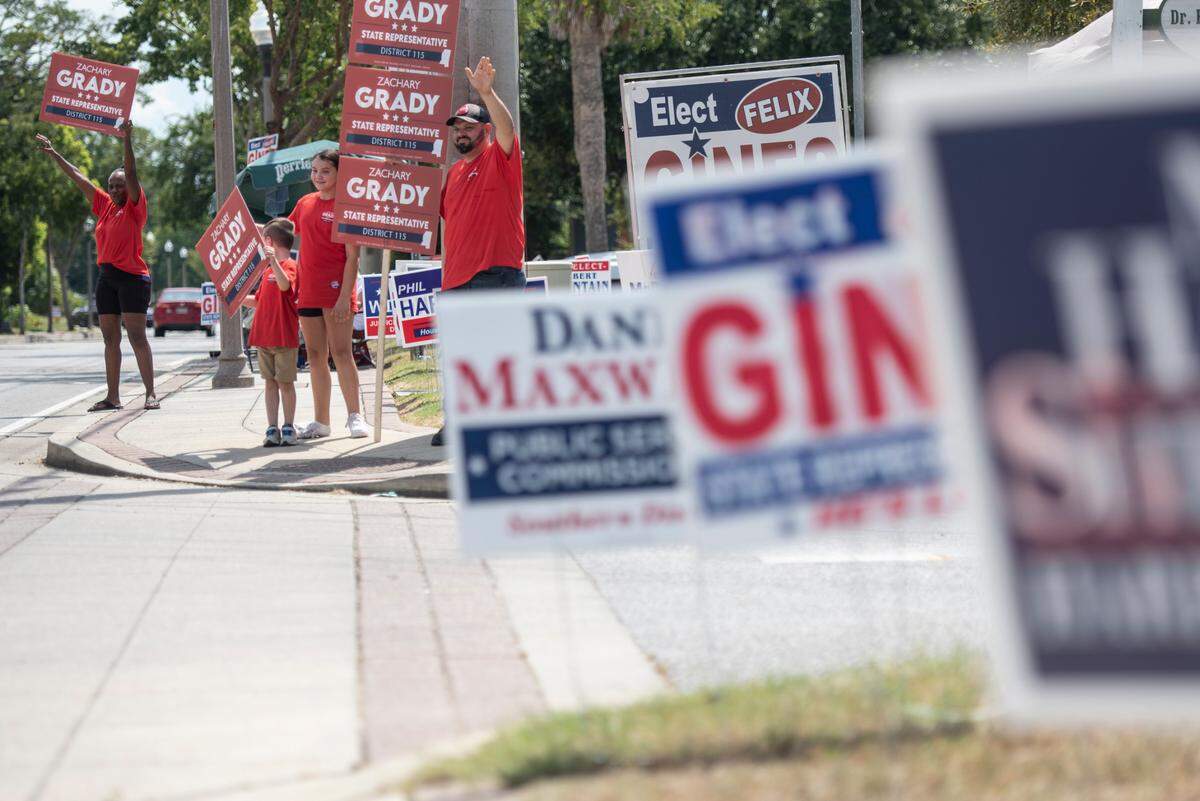 Zach Grady, a candidate for state representative, and his family and supporters wave to passerby outside a polling location at Dr. Frank Gruich Sr. Community Center in Biloxi during the Mississippi Primary Election on Tuesday, Aug. 8, 2023.