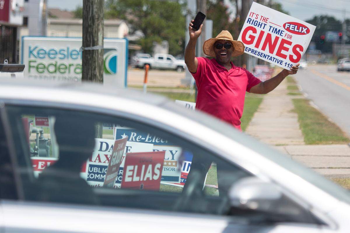 Felix Gines, a candidate for state house representative, waves to a motorist outside a polling location at D’Iberville Civic Center in D’Iberville during the Mississippi Primary Election on Tuesday, Aug. 8, 2023.