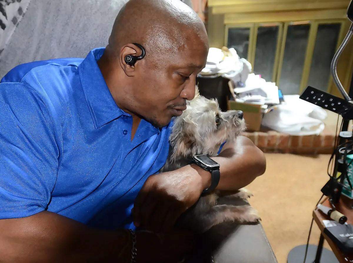 Veteran law enforcement officer Darryl Norwood hugs his dog King, at his south Jackson home, Friday, July 19, 2024. Norwood was permanently disabled after he was shocked with a stun gun in the back of his head by a Jackson police officer.