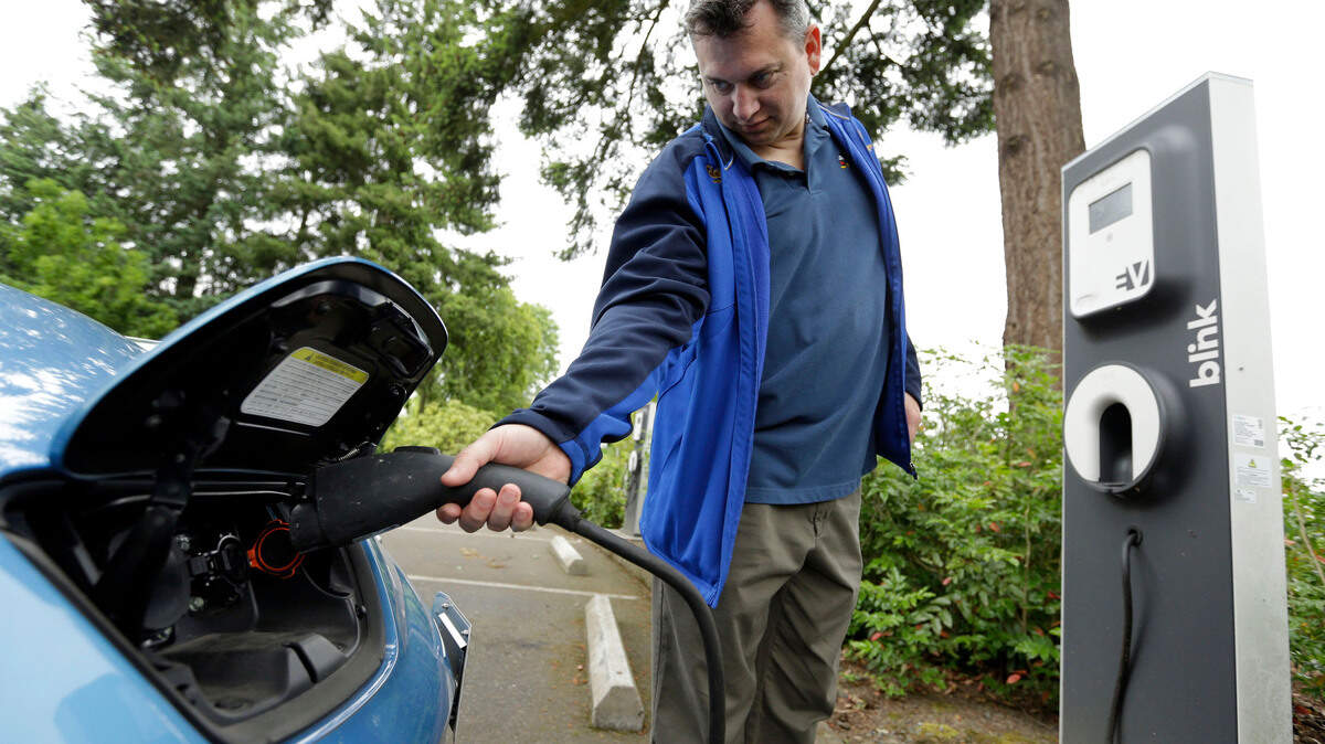 A man charges up his Nissan Leaf at a charging station at a public library in Hillsboro, Ore., in 2015.