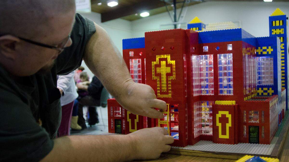 ANDREW WHITAKER/MLIVE.COM VIA APJohn Kraemer places windows on the Lego church that he built in Thomas Township, Mich. Kraemer designs and builds a church out of Legos and displays it at his church each year as a Christmas season tradition.