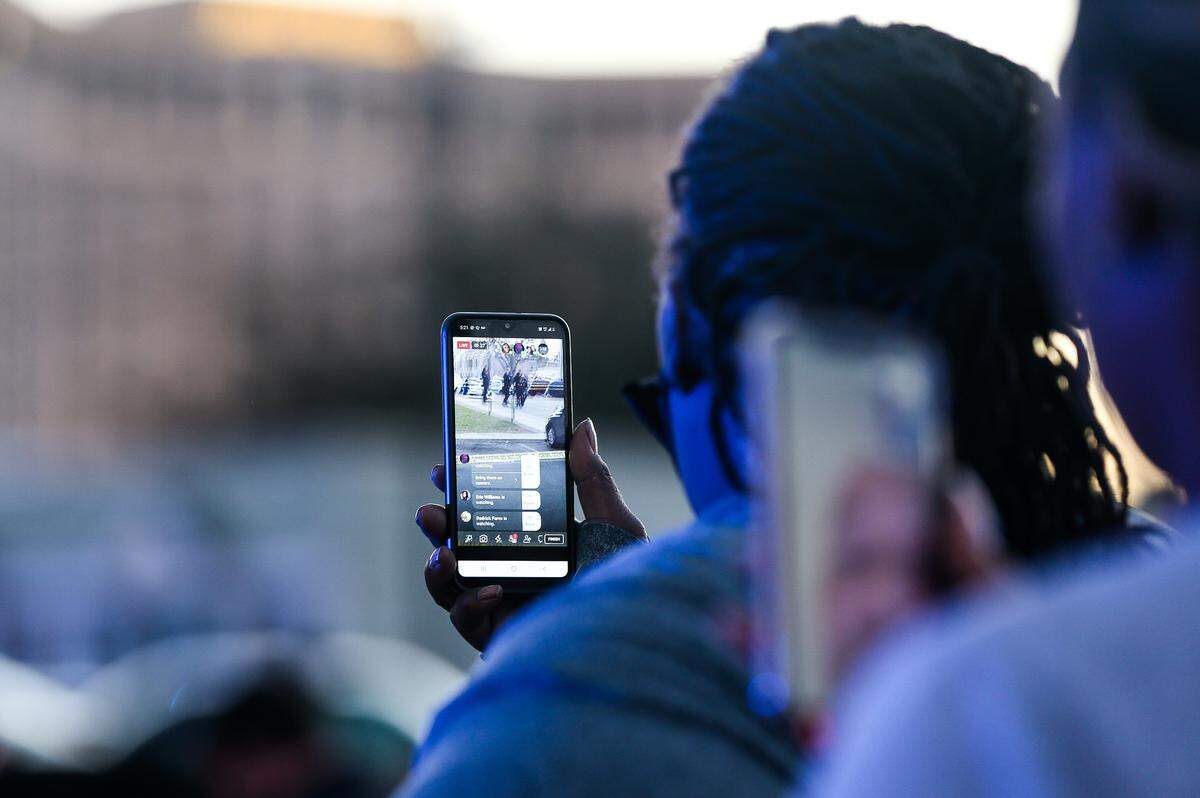 A woman livestreams the scene where a man was shot and killed during an incident involving a Harrison County Sheriff’s deputy at the Biloxi courthouse Friday, Jan. 16, 2021.