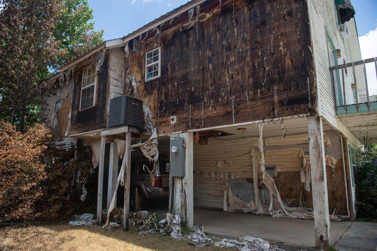 Melted shingles hang off the side of a home on Highway 603 in Kiln on Tuesday, May 31, 2022 after a fire broke out in the neighboring two houses on Saturday night, killing two.