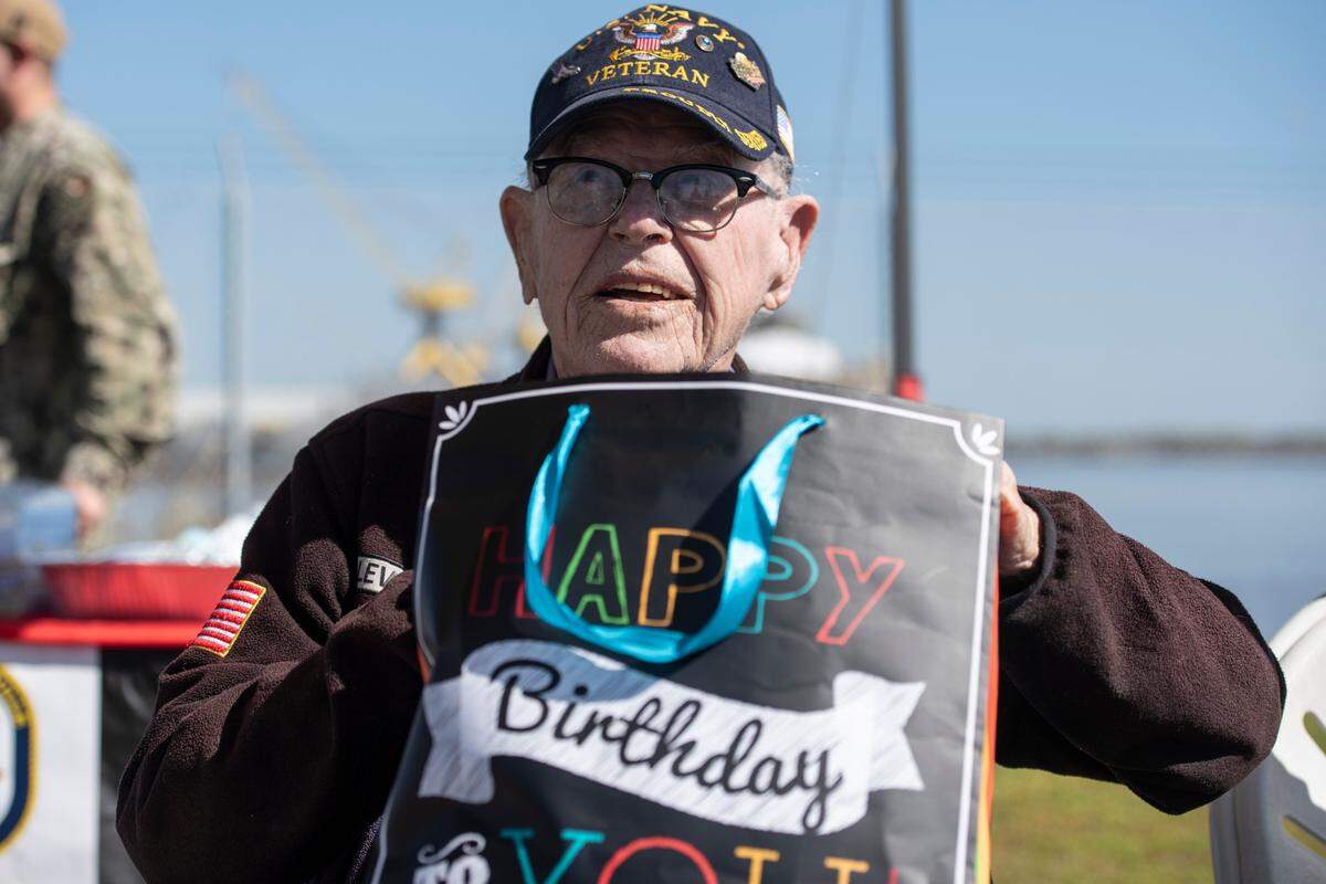Alfred Lewis, a WWII veteran who fought in Iwo Jima, opens a birthday gift from the crew of the USS Bougainville during a ceremony for Lewis at Singing River Island in Pascagoula on Saturday, March 22, 2025.