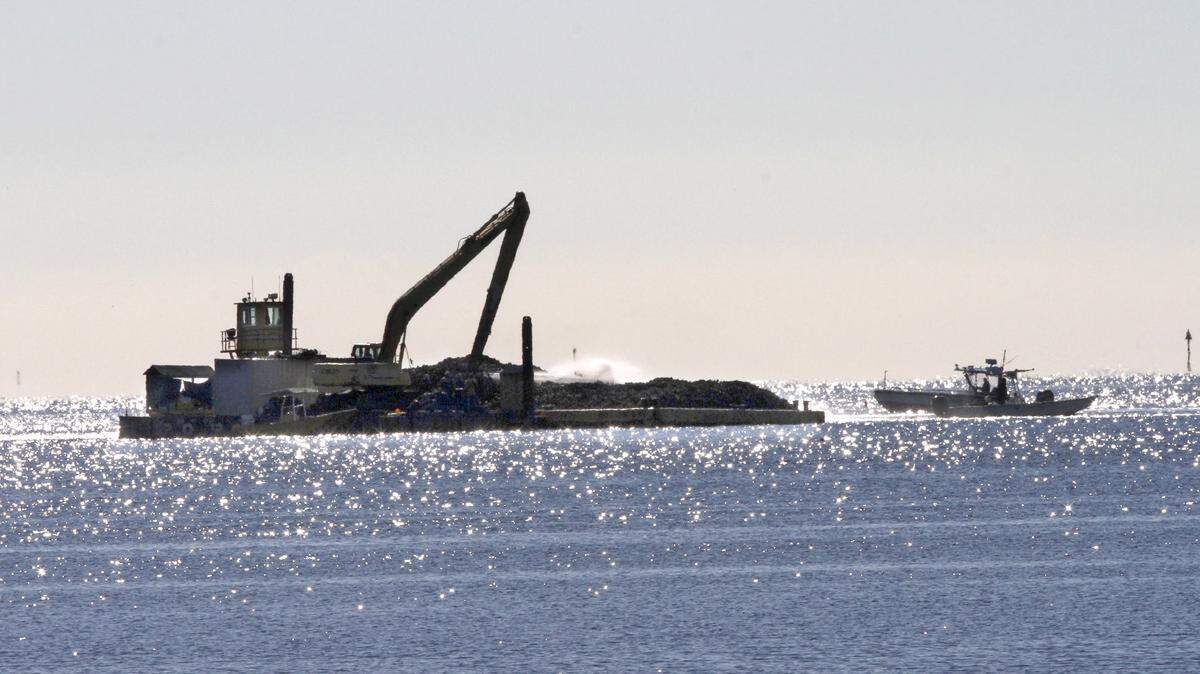 TIM ISBELL/SUN HERALD 
 A boat get close to a barge as oysters are washed off by high pressure water hose in Biloxi Bay, Tuesday, Jan. 19, 2016. Oysters are being moved out of harm's way from the freshwater intrusion created by the opening of the Bonnet Carre Spillway.