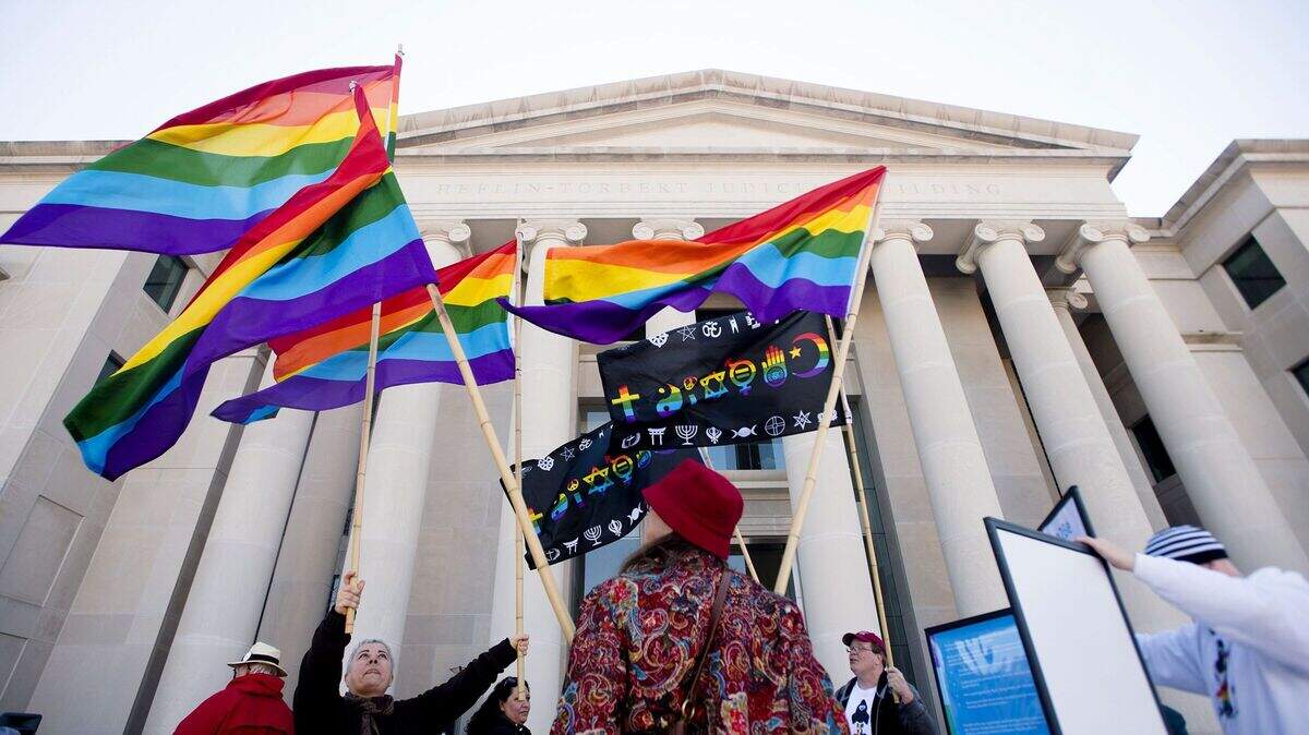 Minoo Vafai, left, holds rainbow flags with others during a rally against Alabama Chief Justice Roy Moore on Tuesday, Jan. 12, 2016, outside the Alabama Supreme Court building in Montgomery, Ala. Supporters of gay marriage rallied Tuesday against Moore and his opposition to same-sex marriage. (Albert Cesare /The Montgomery Advertiser via AP) NO SALES; MANDATORY CREDIT