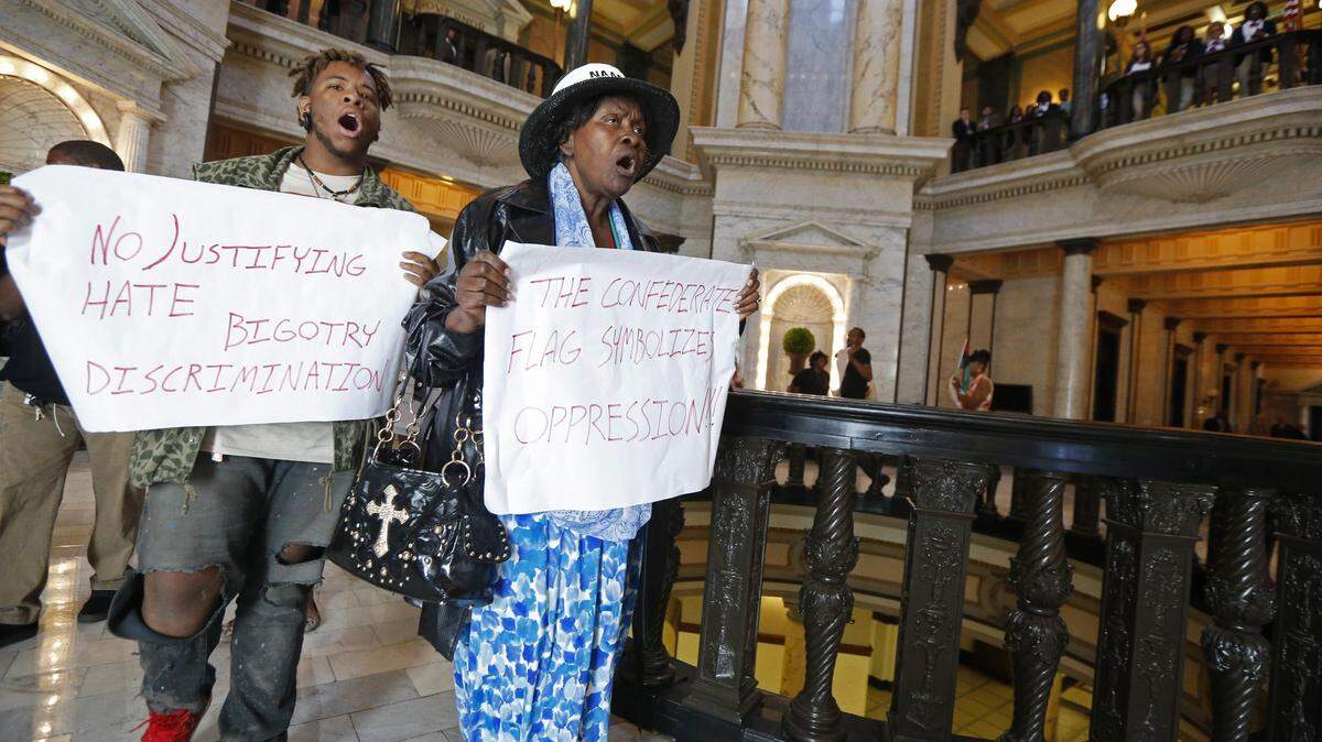 Ineva May-Pittman, right, of Jackson, Miss., leads a chanting flash protest around the Capitol rotunda in Jackson, Miss., Monday, April 4, 2016. About two dozen protesters marched for several minutes holding signs and chanting against a bill that would expand the Jackson airport board and against Confederate symbols used by the state. (AP Photo/Rogelio V. Solis)