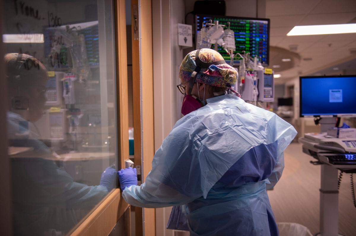 A nurse enters a COVID-19 patient’s room in the ICU at Memorial Hospital in Gulfport on Wednesday, Aug. 11, 2021.