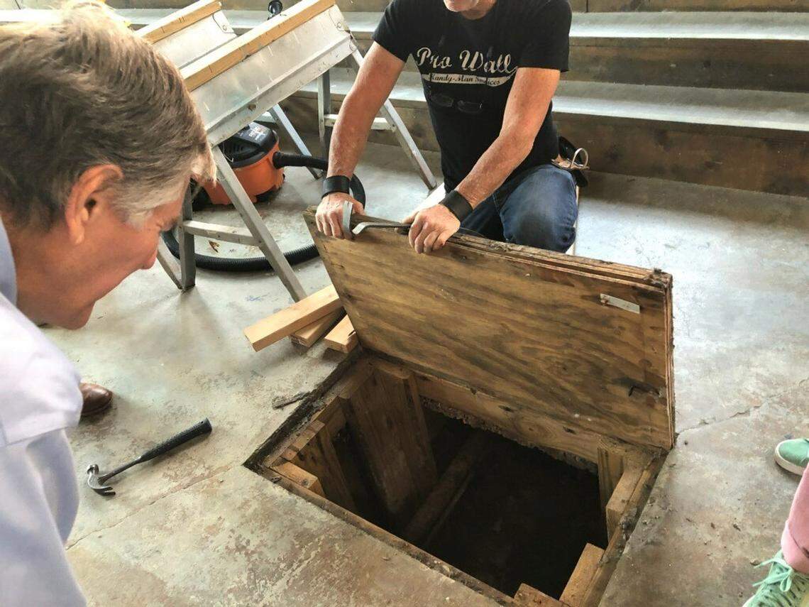 Biloxi Mayor Andrew “FoFo” Gilich, left, peeks below a trap door in the floor at the new Ground Zero Blues Club Biloxi to see a tunnel that was used to secretly transport alcohol through downtown during Prohibition.