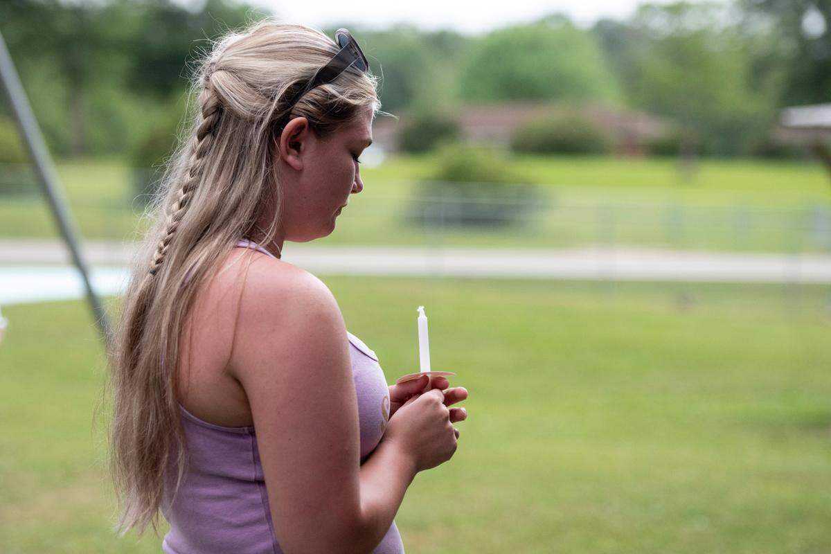 Community members hold candles and pray during a candlelight vigil in remembrance of Gracelynn Vick at Saucier Park on Tuesday, April 22, 2025.
