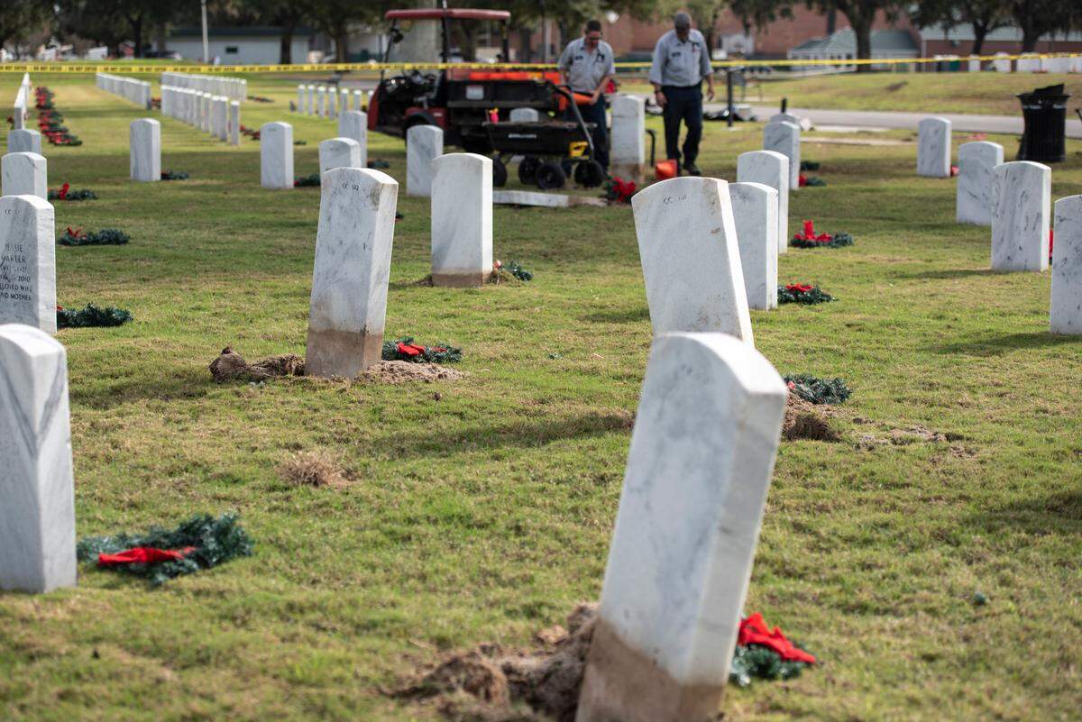 Workers fix headstones at Biloxi National Cemetery in Biloxi on Monday, Dec. 4, 2023, after a driver of a pickup truck ran them over on Sunday.
