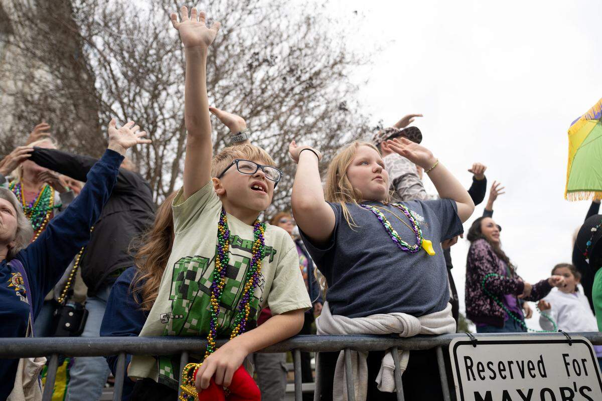 Children reach out to catch Mardi Gras throws.